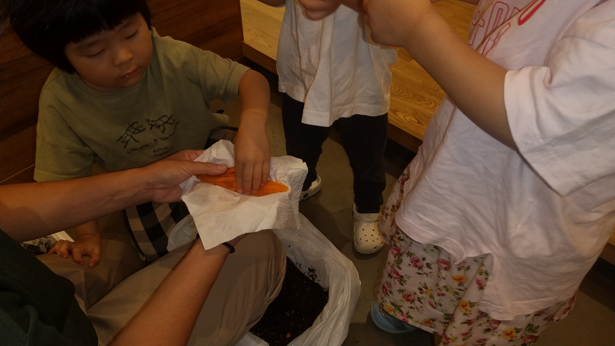 コンポストに野菜の皮を入れていく子どもたち