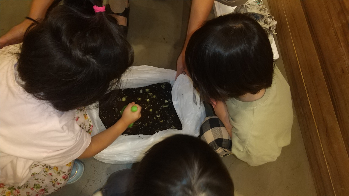 コンポストの土を混ぜる子どもたち