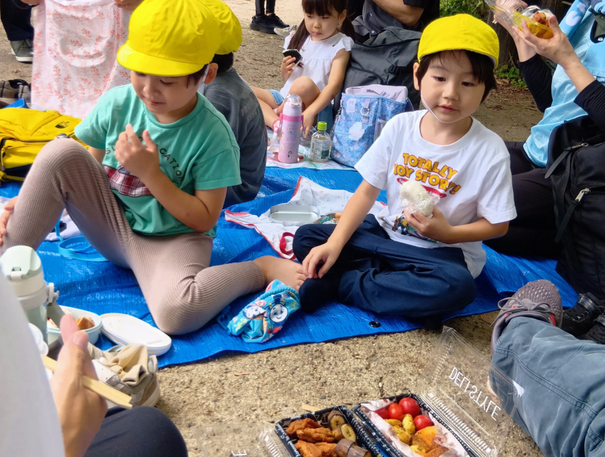 山頂でお弁当を食べる子どもたち