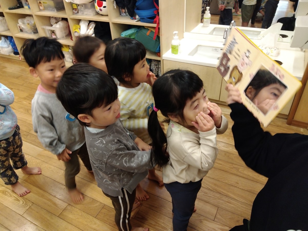 絵本の鏡に向かって表情を作る子どもたち