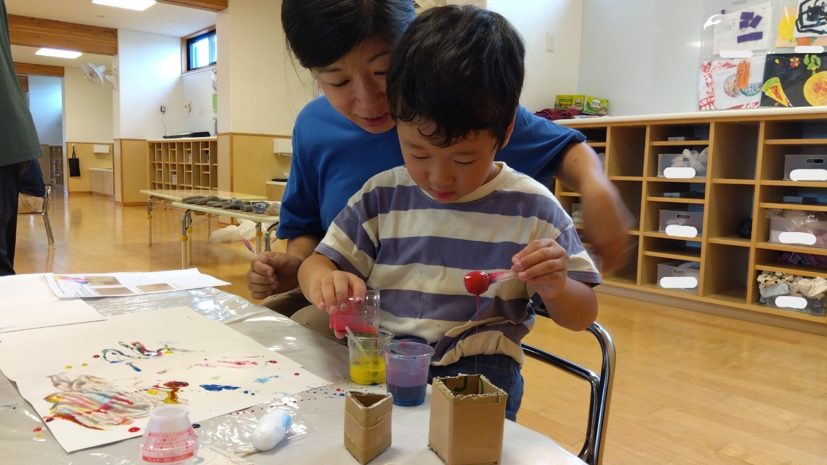 絵の具の色水を混ぜる子ども