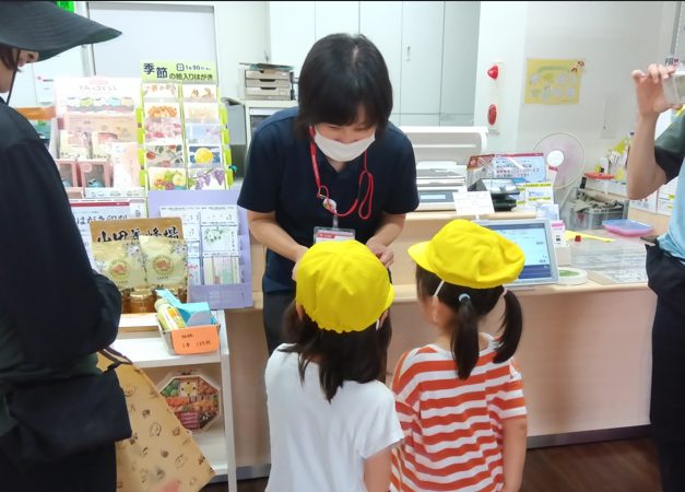子どもからひまわりの種を受け取る郵便局職員