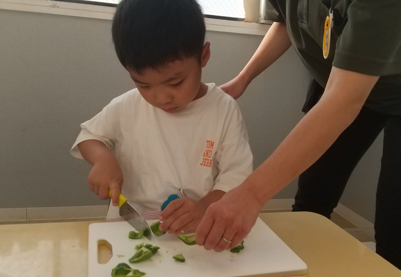 包丁を使ってピーマンを切る子ども