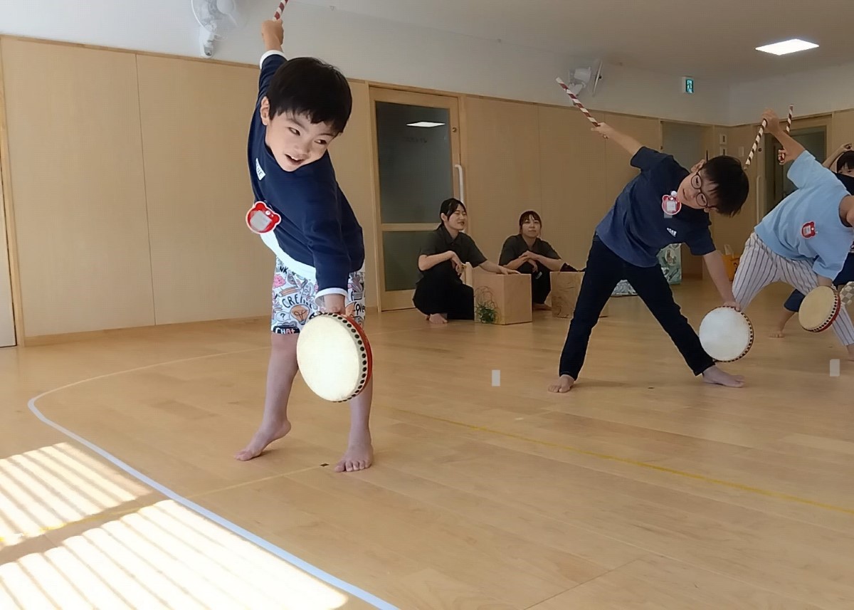 太鼓とバチを持って踊る子どもたち