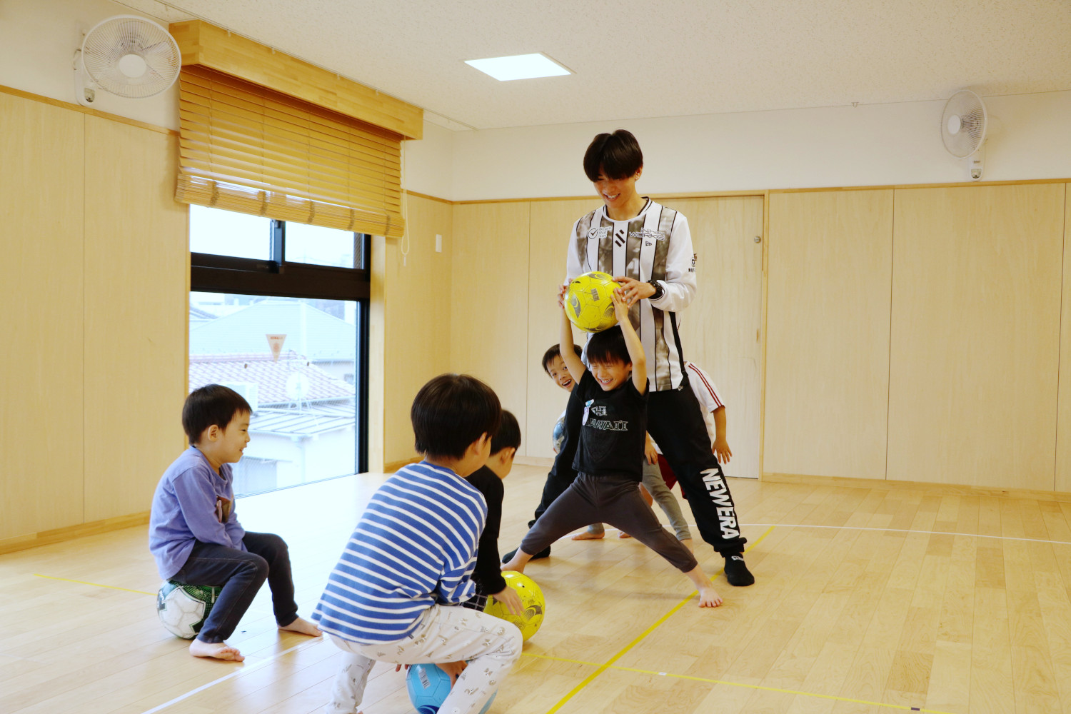 一列に並び足を開く子どもたちと選手。足の間にボールを通そうとする子どもたち