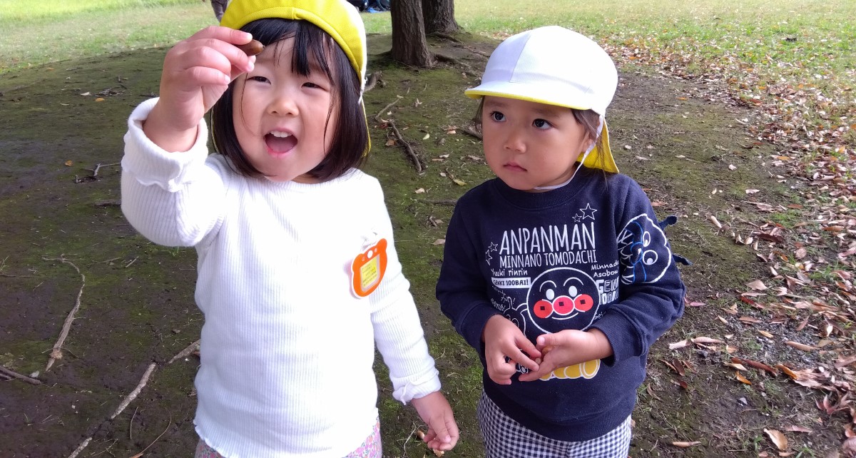 拾ったどんぐりを見せる子ども
