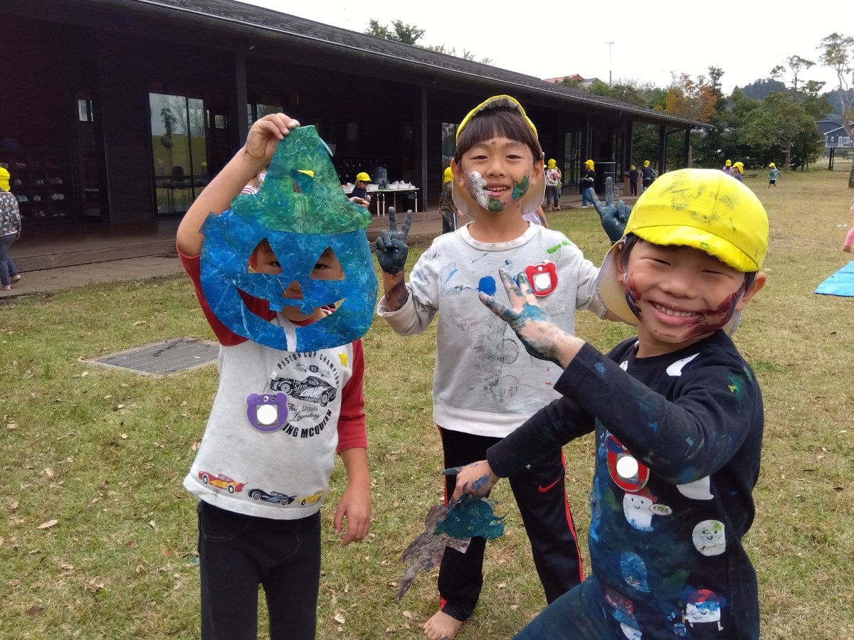 カボチャの切り抜きをお面にして見せる子どもたち