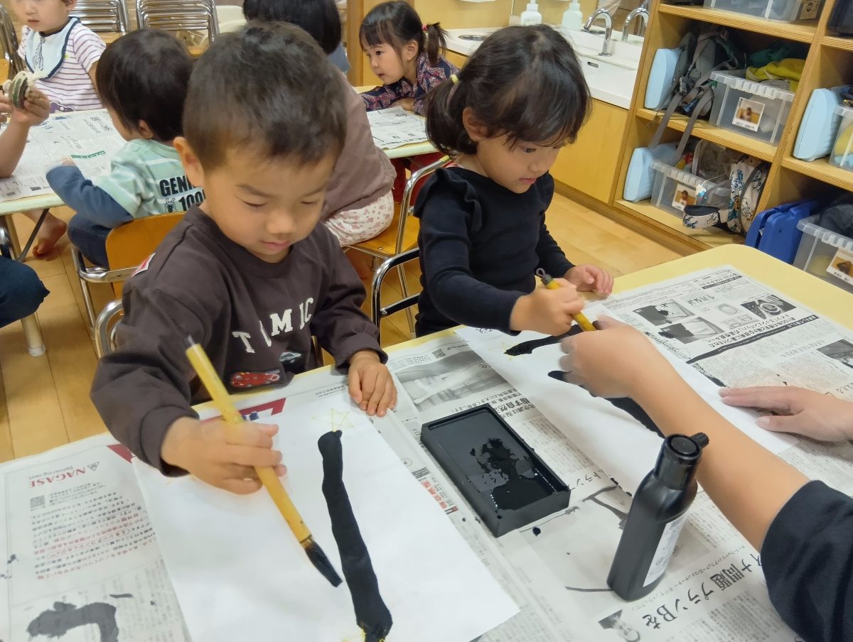 筆で半紙に線を引く子どもたち