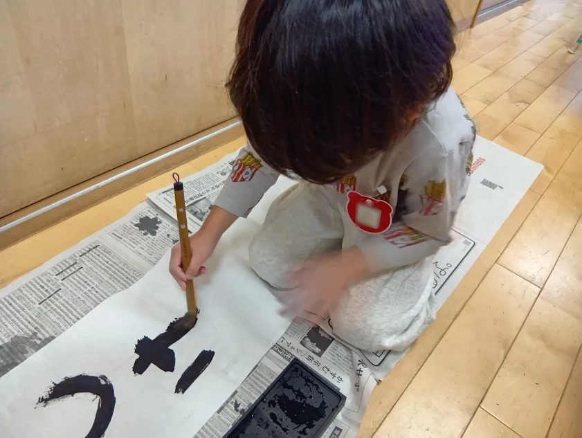 磨った墨で字を書く子ども