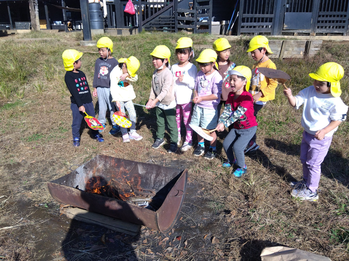 焚き火を団扇で扇ぐ