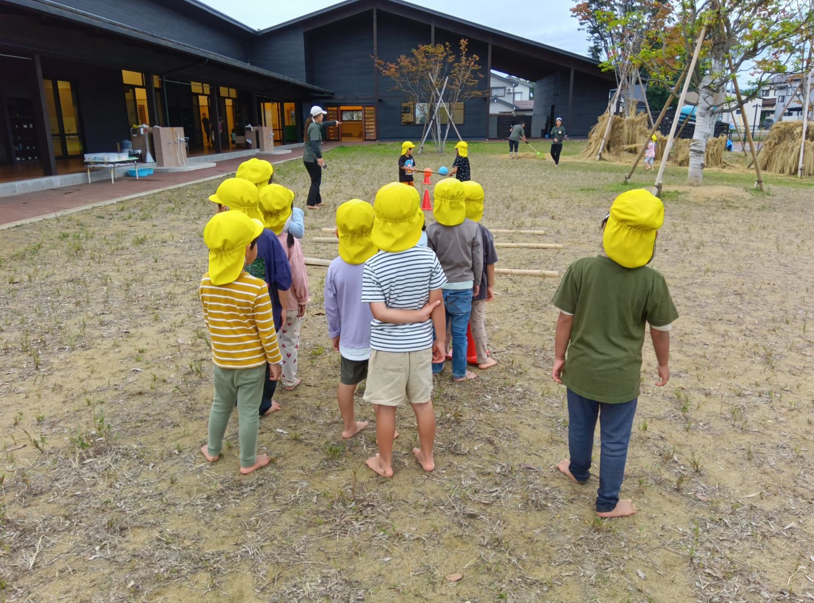 竹でボールを挟み、2人で協力して運ぶ子どもたち