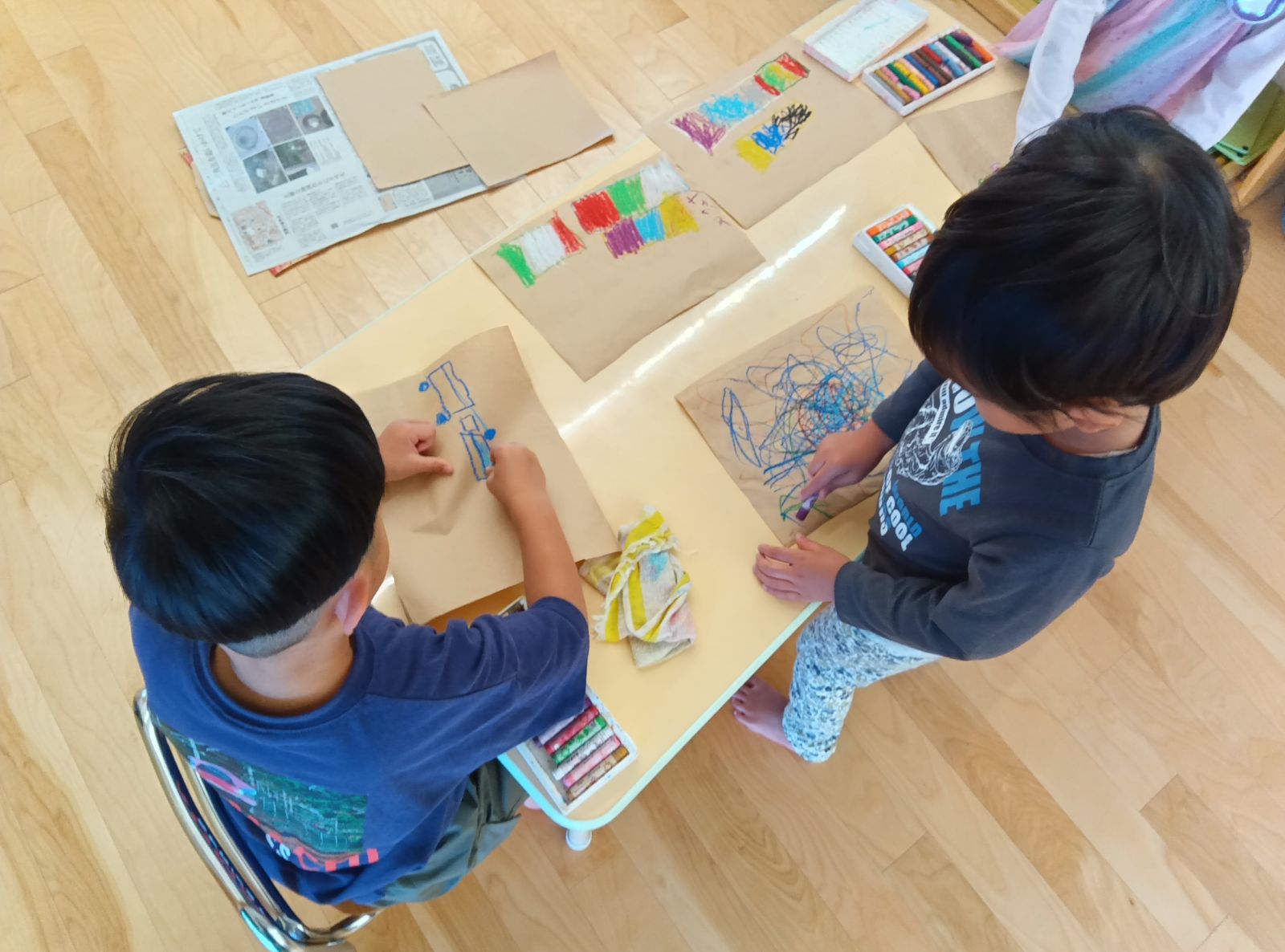 紙にクレヨンで絵を描く子どもたち