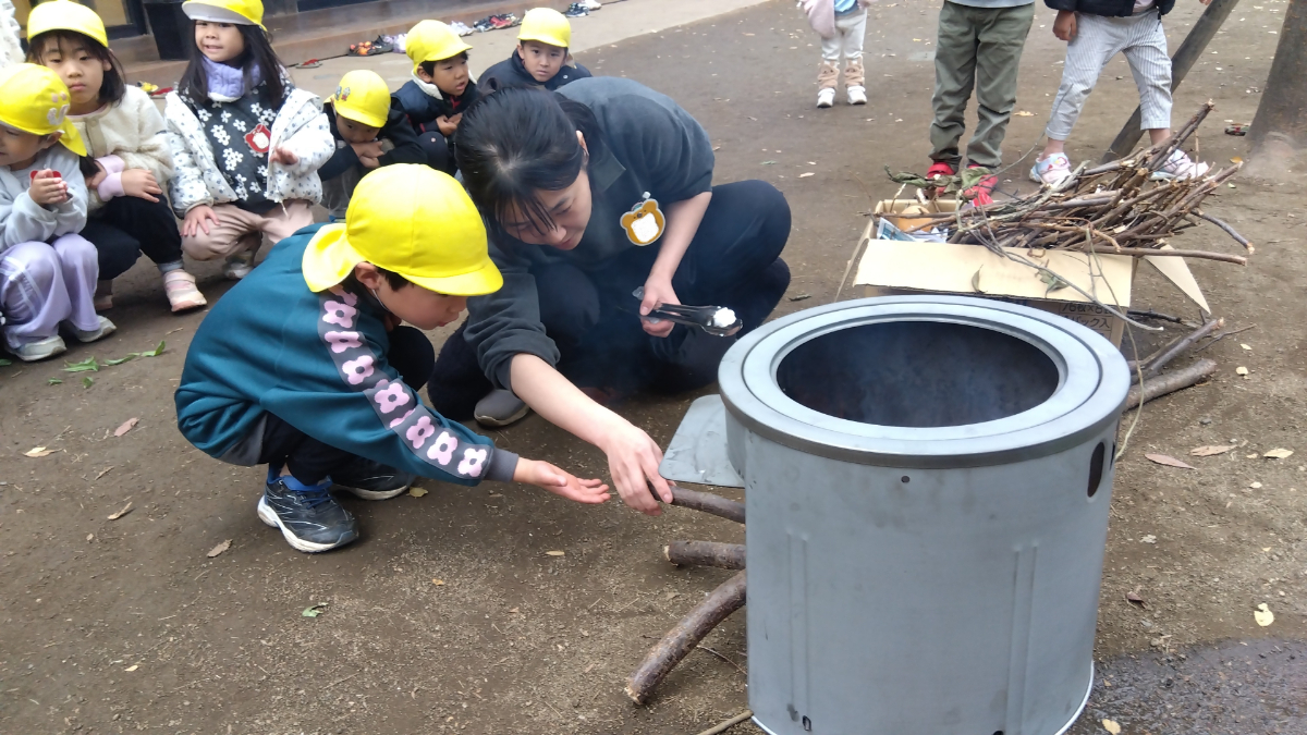 かまどに枝を入れる