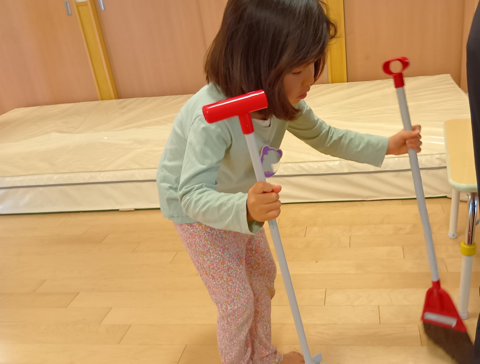 床をほうきで掃く子ども