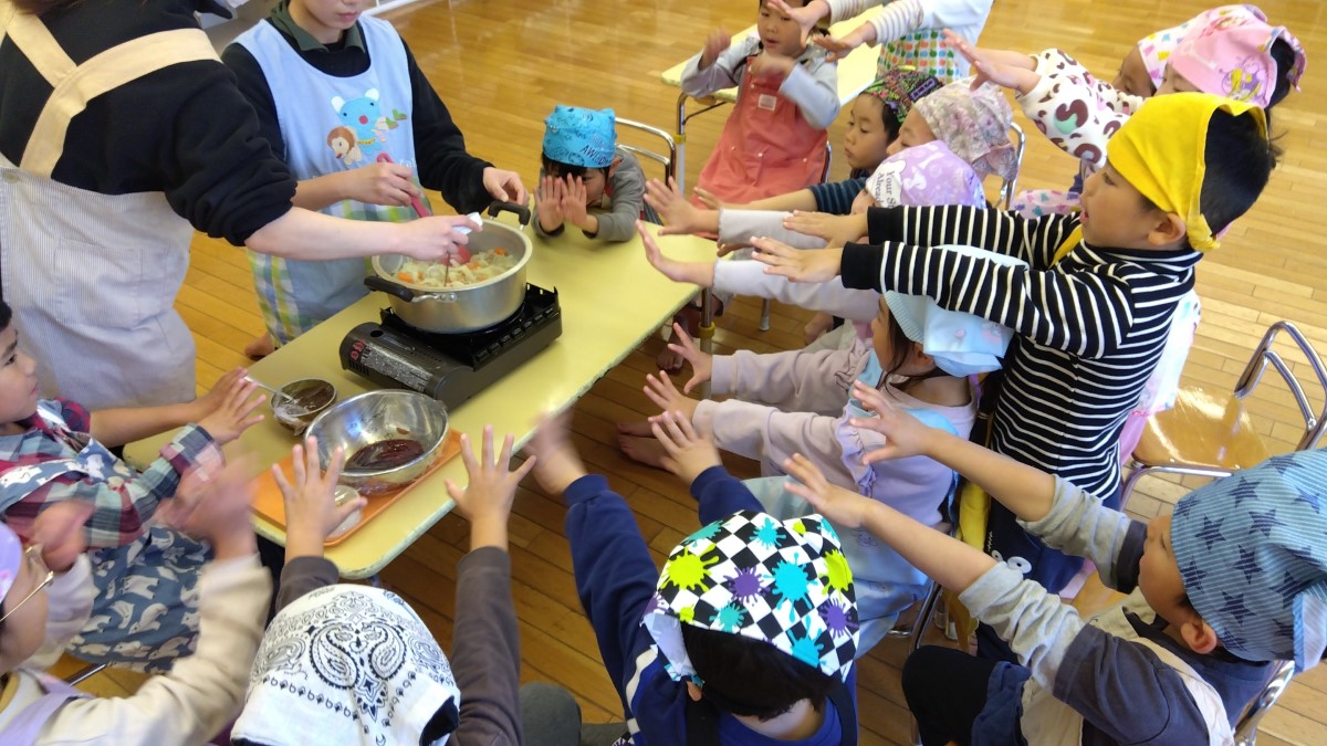 鍋に手を伸ばしパワーを送る子どもたち