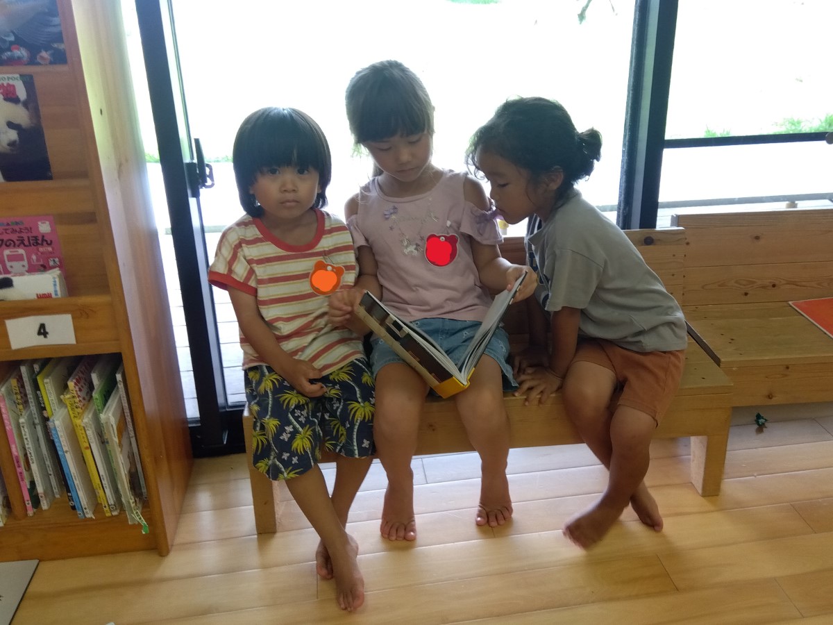 3人で1冊の本を読む子どもたち