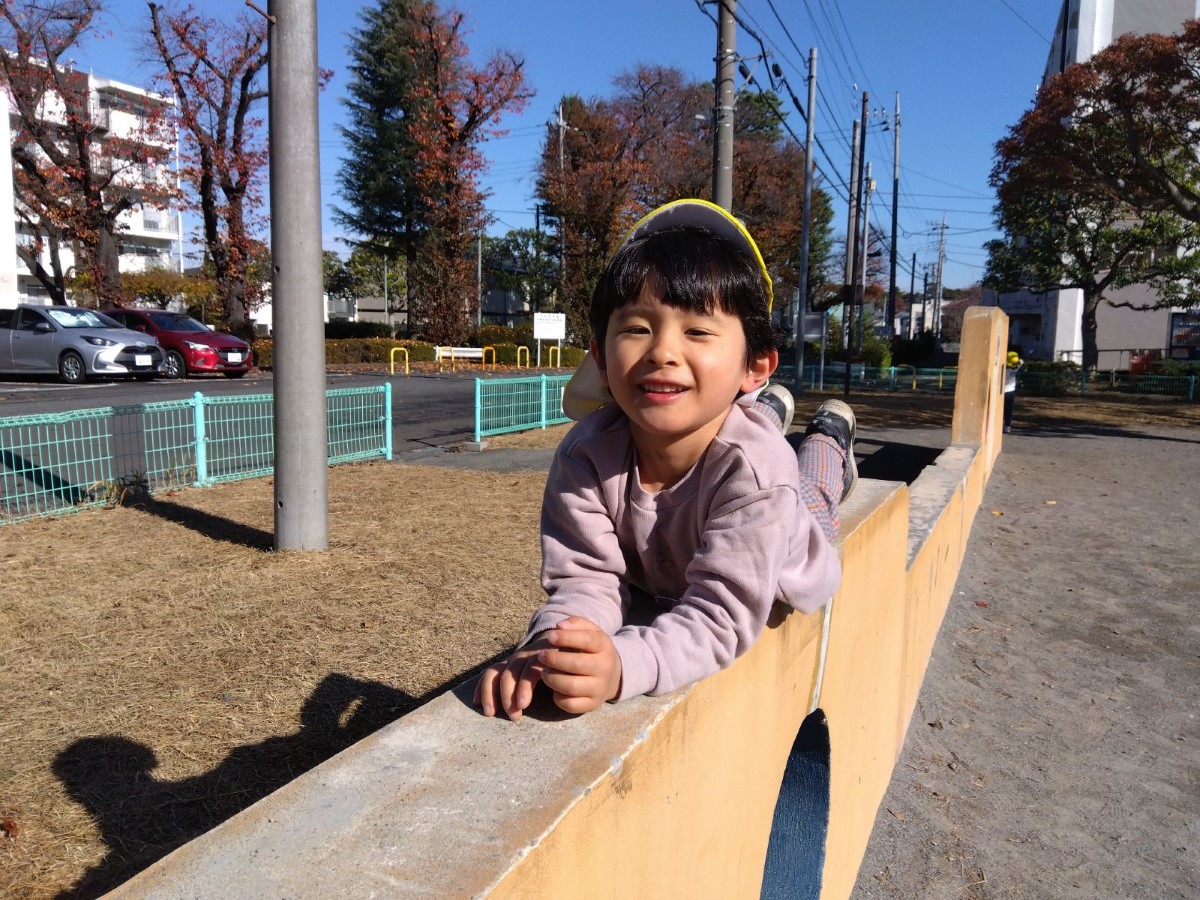 塀の上に寝そべる子ども