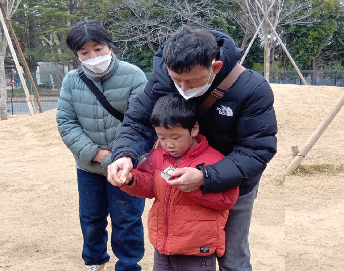 大人の手を借りながらマッチを使う子ども