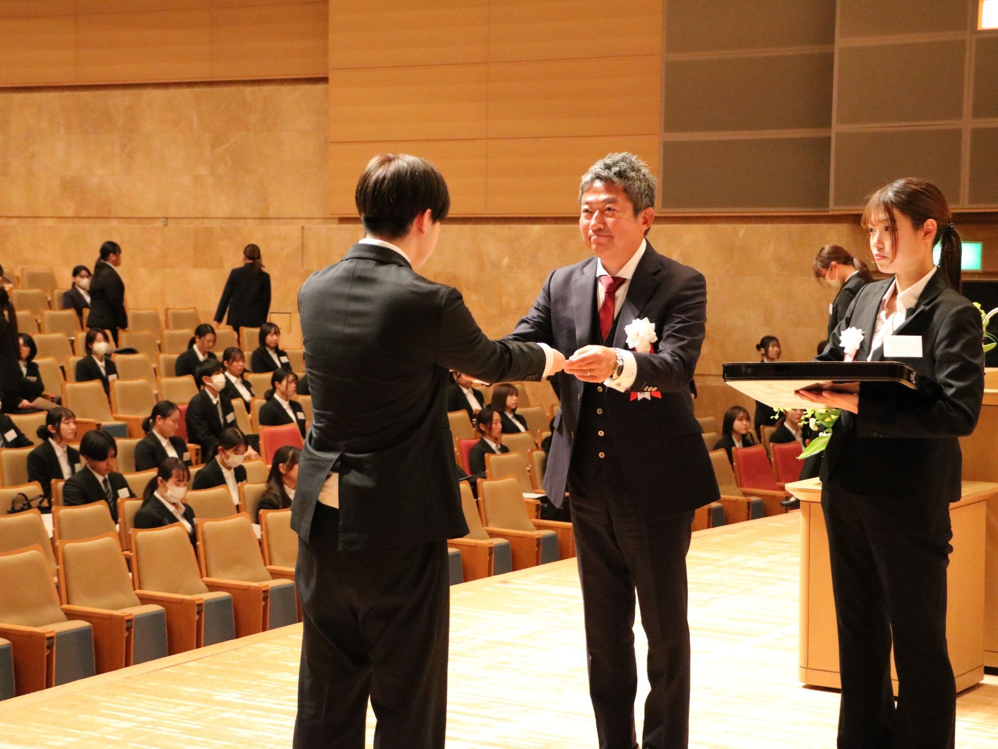 壇上で高堀代表から内定証書を受け取る内定者