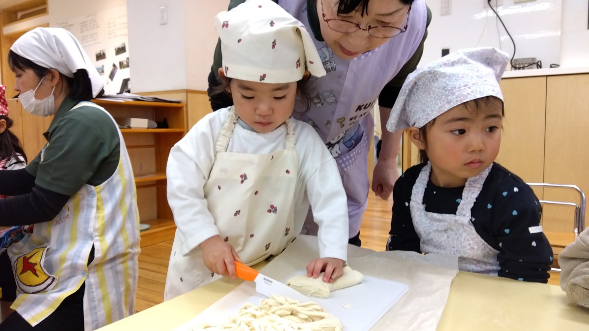 包丁でうどん生地を切る子ども