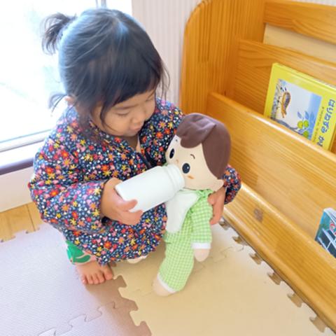 人形にミルクを飲ませる子ども