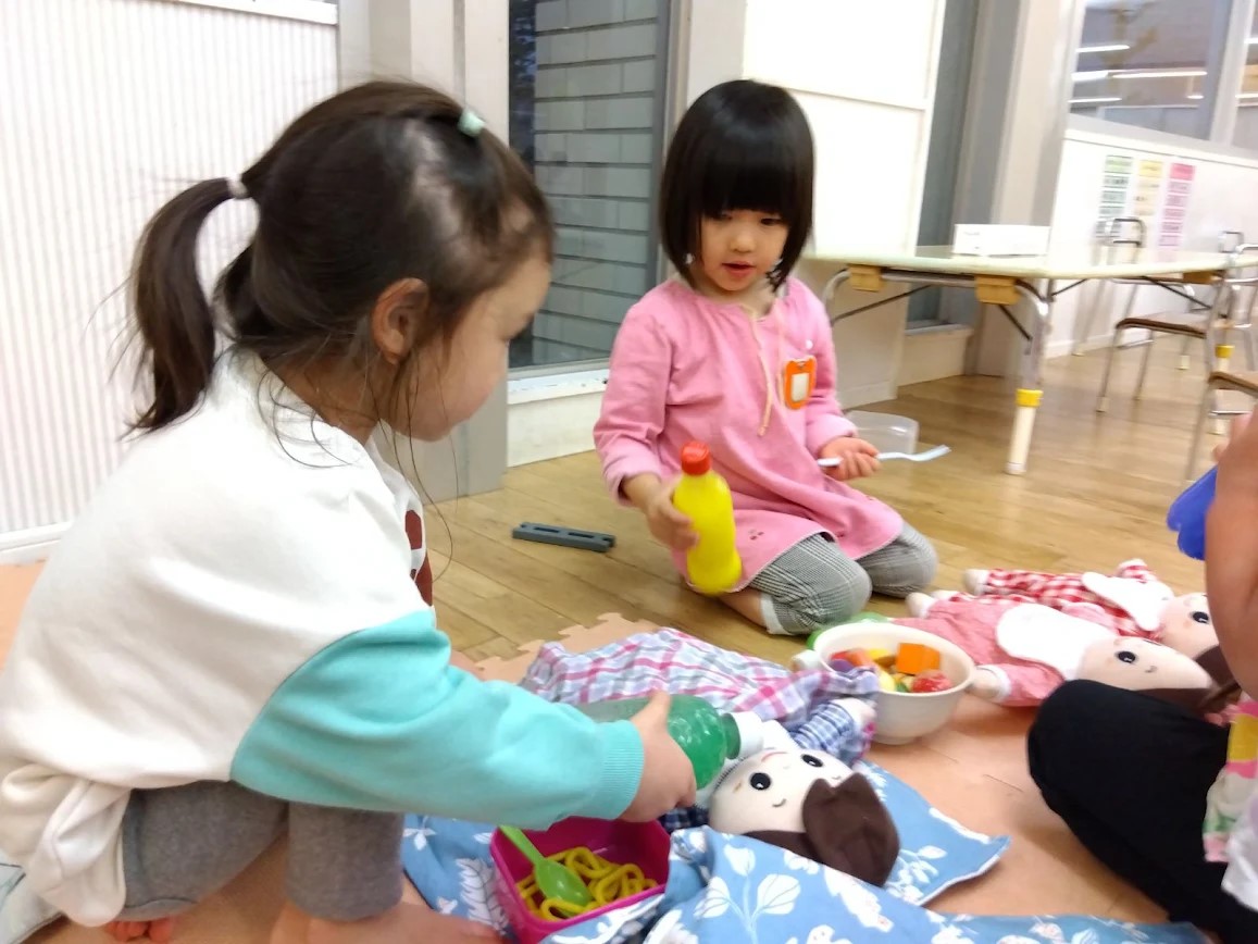 子どもを布団に寝かせてお世話をする子どもたち