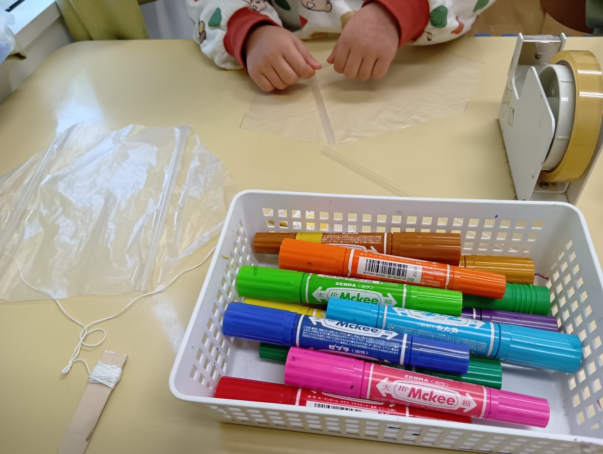 ビニール袋にストローを貼り付ける子ども