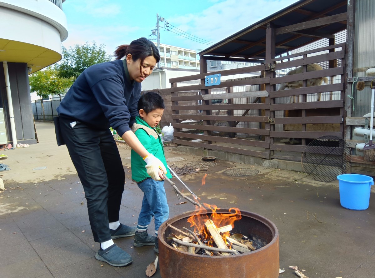 焚き火の中に小枝を追加する子ども