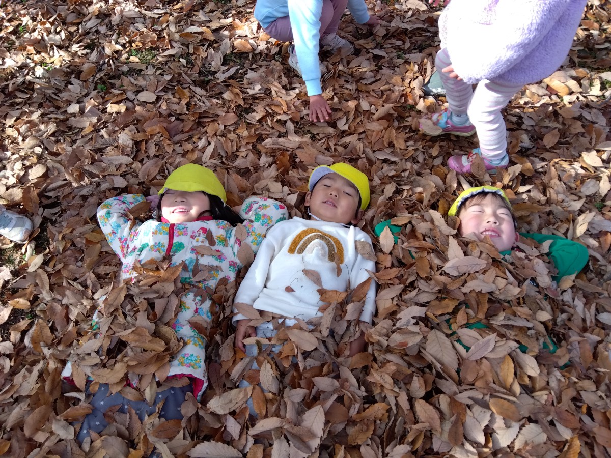 落ち葉に埋もれる子どもたち