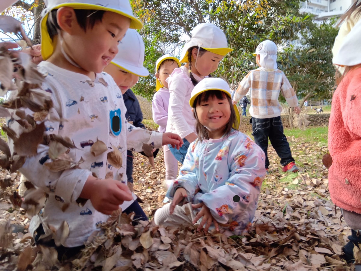 落ち葉を撒いて遊ぶ子どもたち