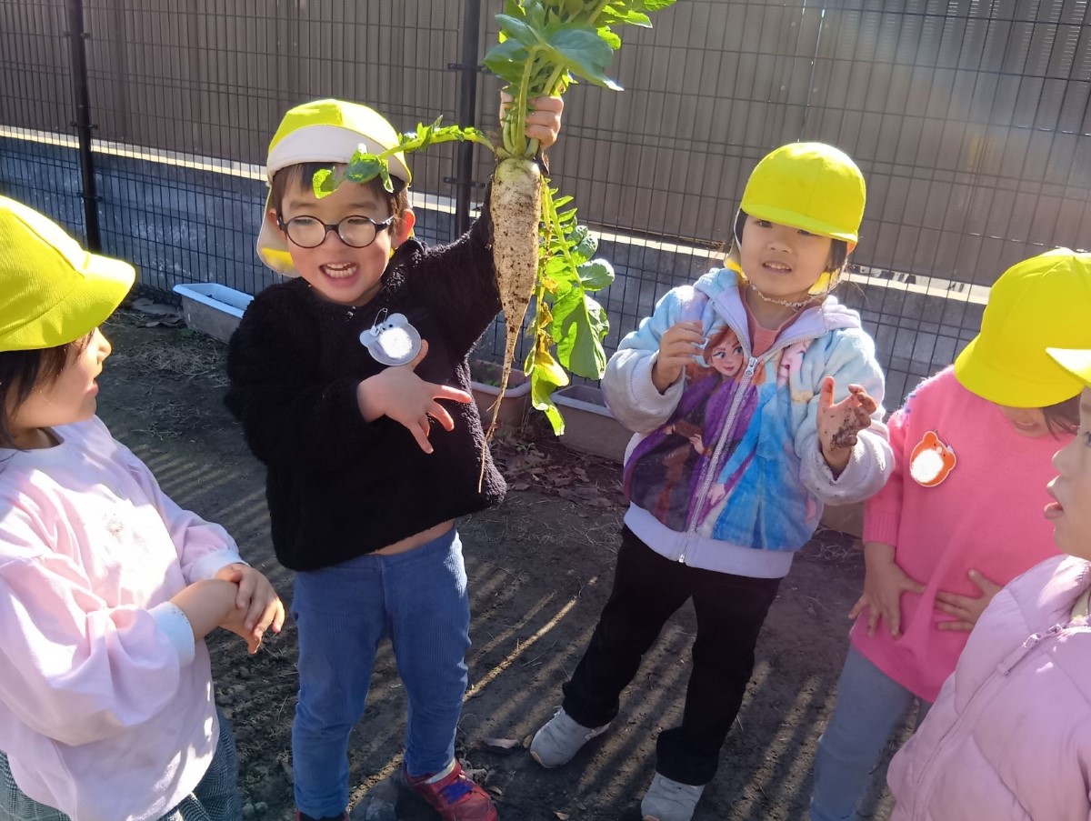 大きな大根を手に持ち、嬉しそうにする子どもたち