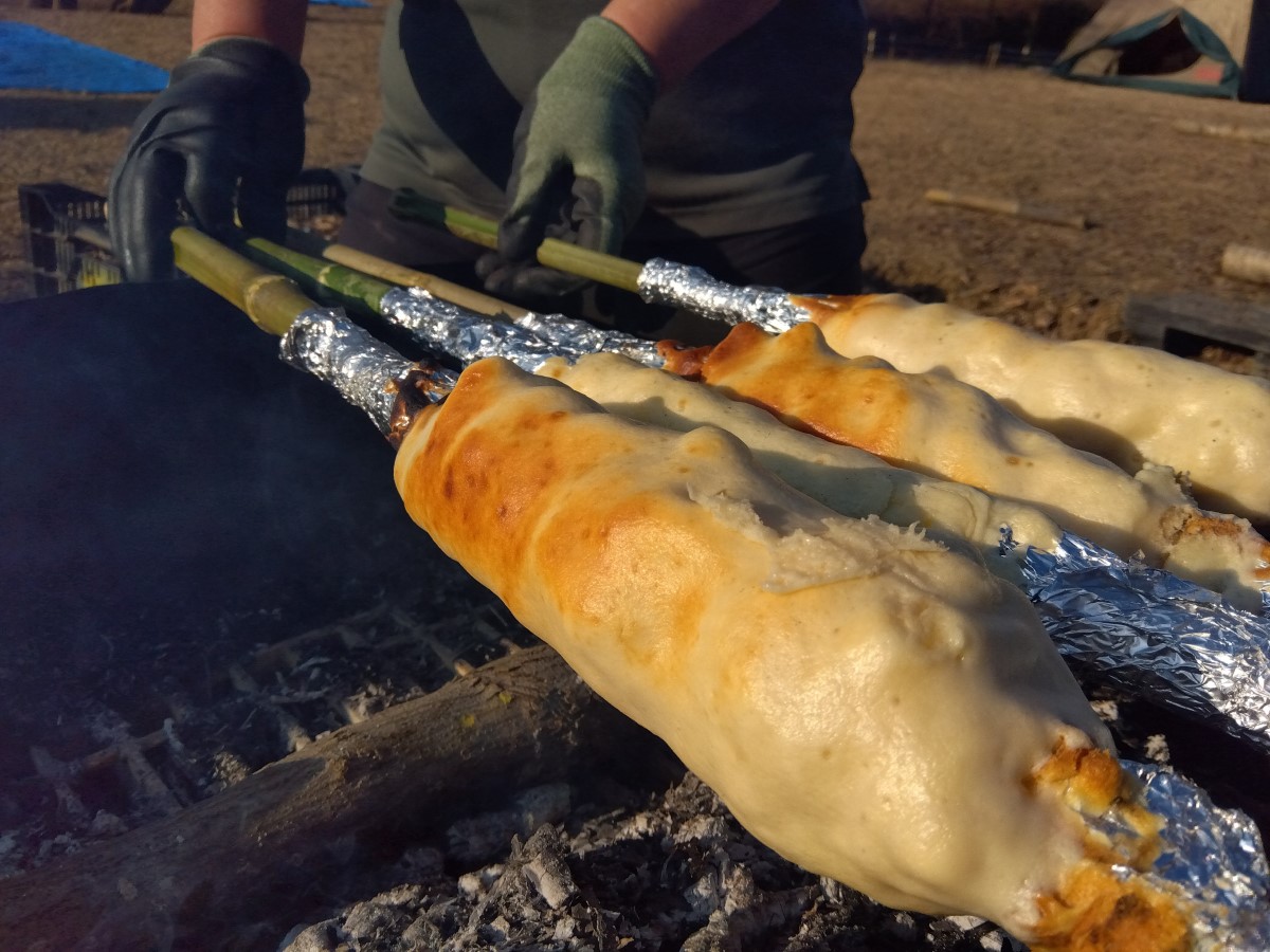 竹に巻いたパン生地を焚き火で焼く様子