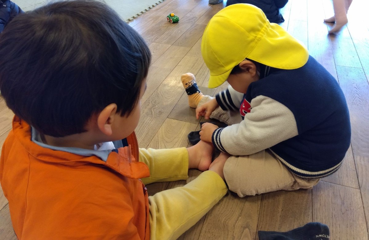 靴下を履かせてあげる子ども