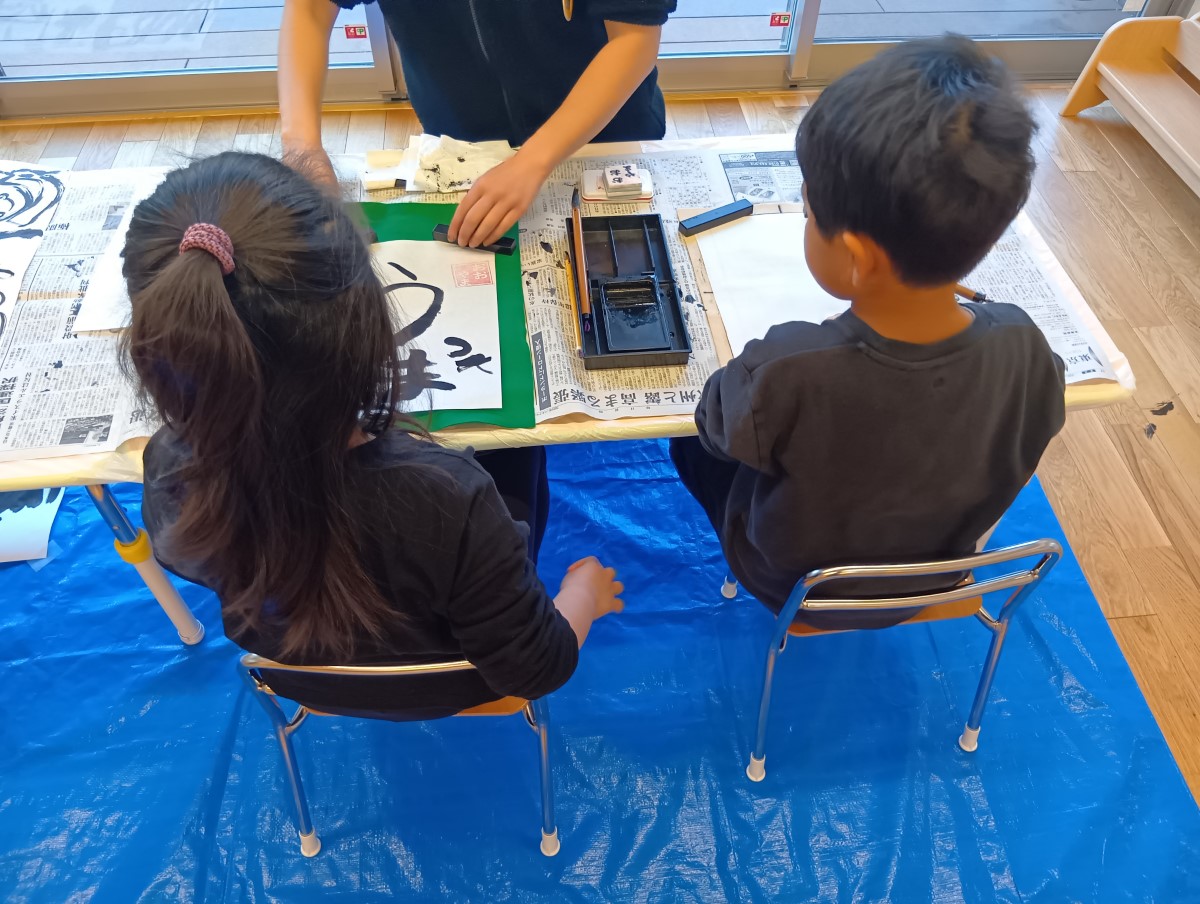 墨で「うま」と書く子ども