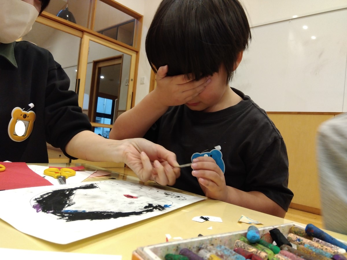 片手で目を抑えながら福笑いを楽しむ子ども