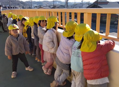 歩道橋の上から車を眺める子どもたち