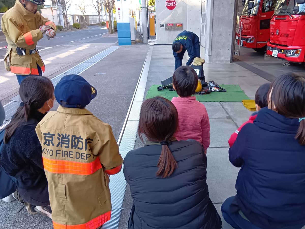 防火服に着替える様子を見る子どもたち