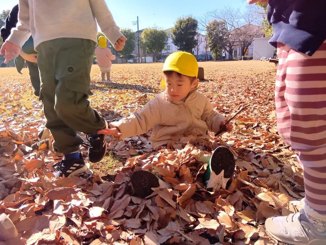 公園で落ち葉に埋もれる子ども