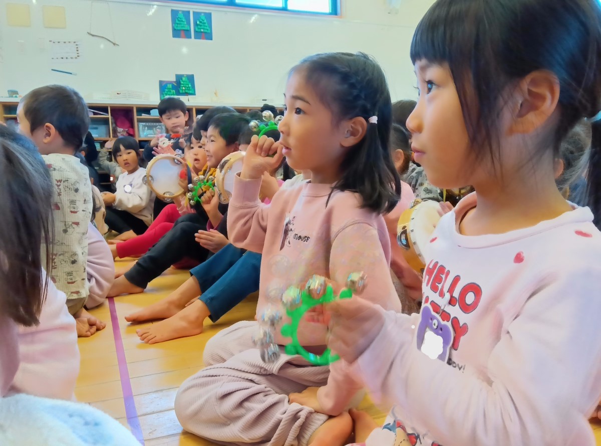 鈴やタンバリンを持って演奏を聴く子どもたち
