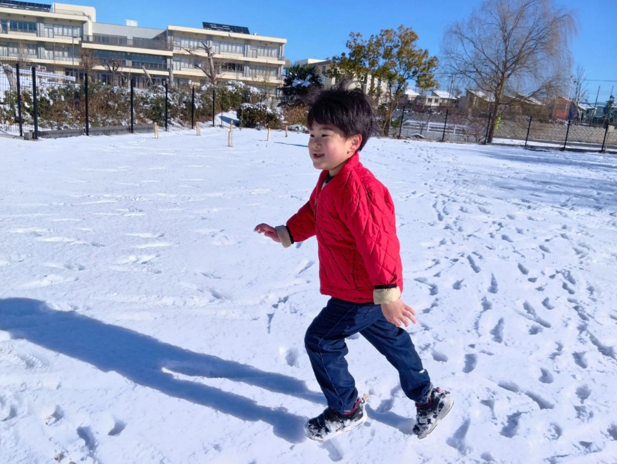 雪の中を楽しそうに走る子ども