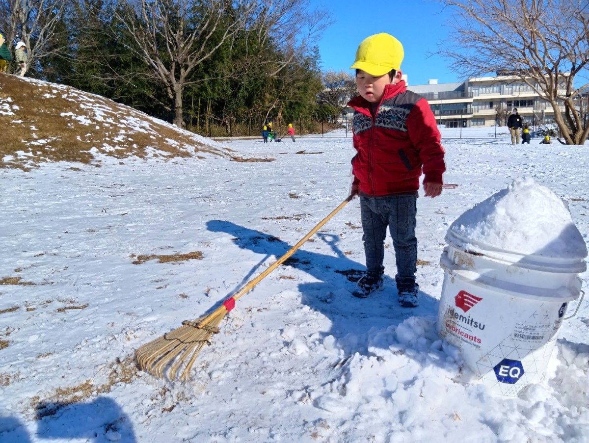 くま手で雪を集める子ども