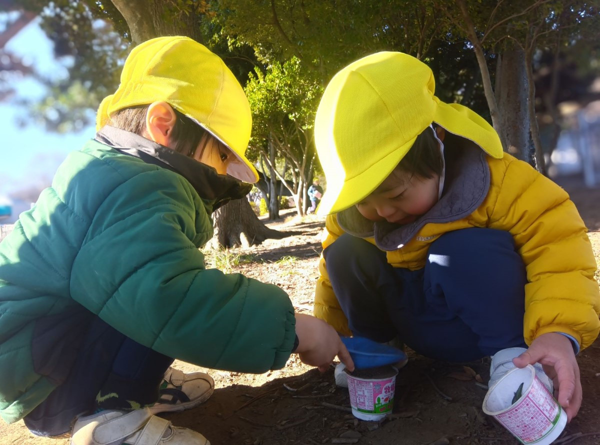 公園で容器に土を入れる子どもたち