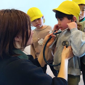 聴診器で自分の心臓の音を聞く子ども