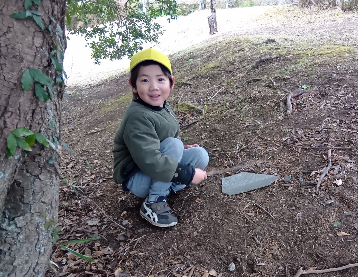 木の棒で段ボールを叩く子ども