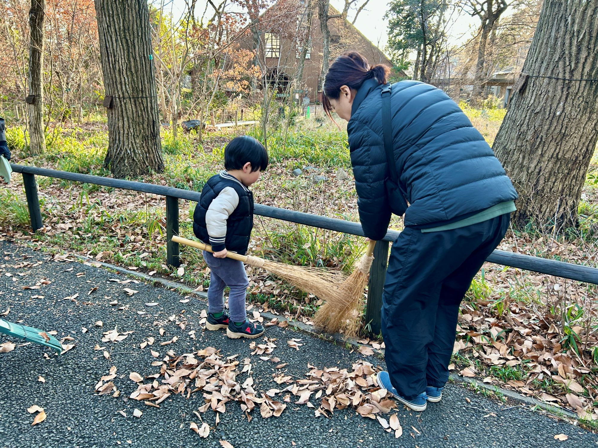 子どもが手作りの箒で葉をかき出す様子