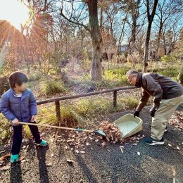 子どもが職員から熊手の使い方を教わる様子