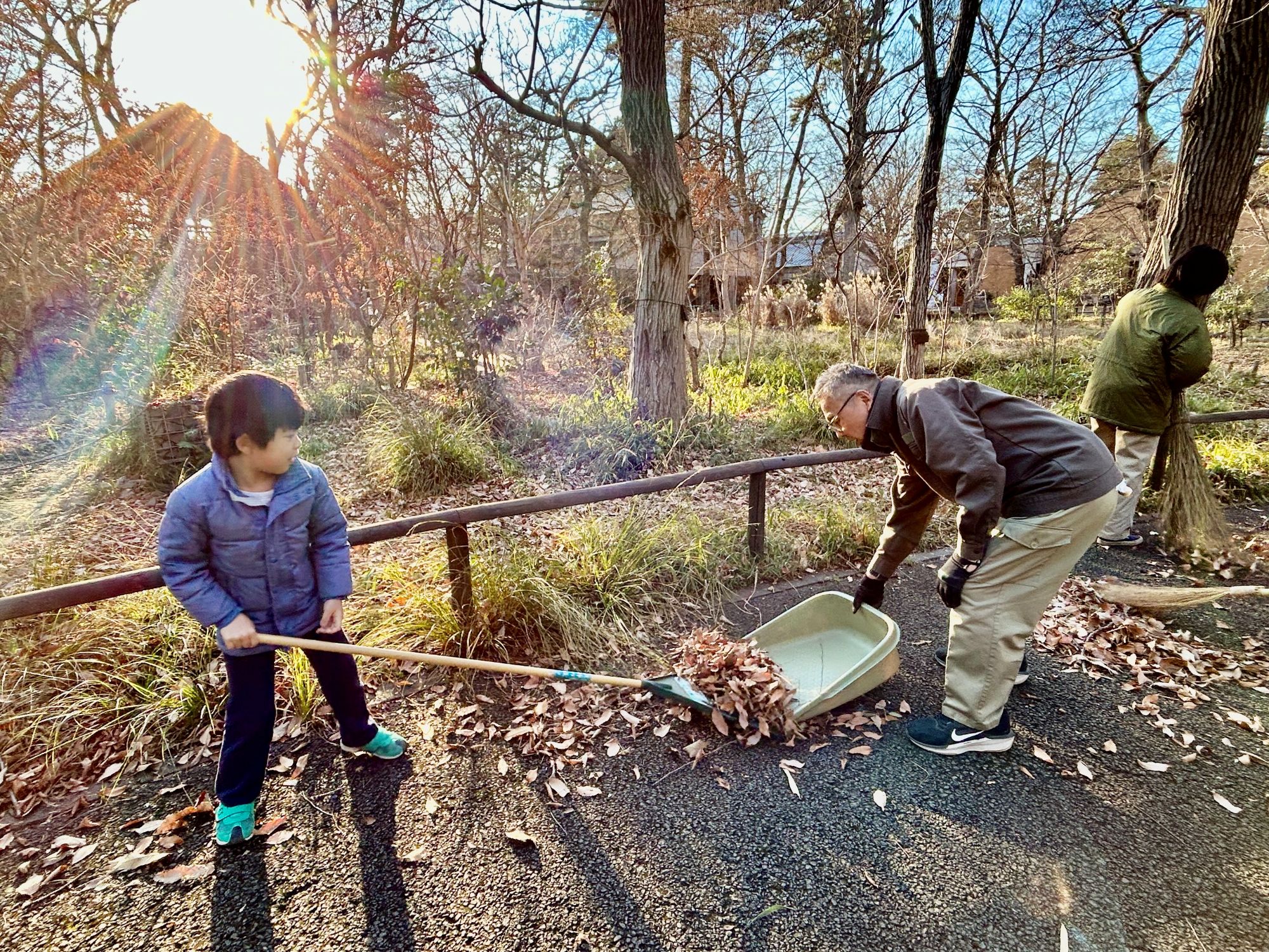 子どもが職員から熊手の使い方を教わる様子