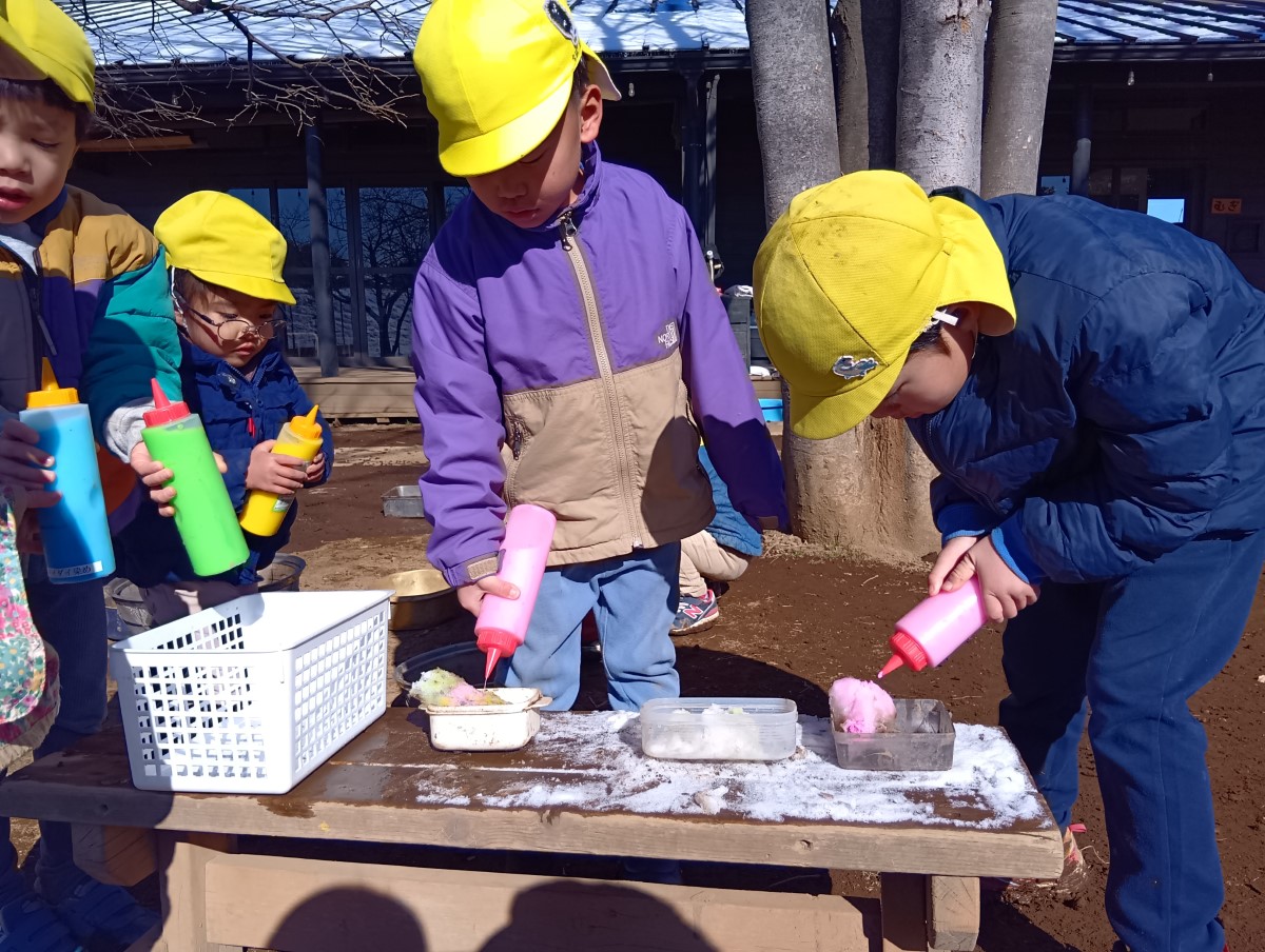 雪に色をつけて遊ぶ子どもたち