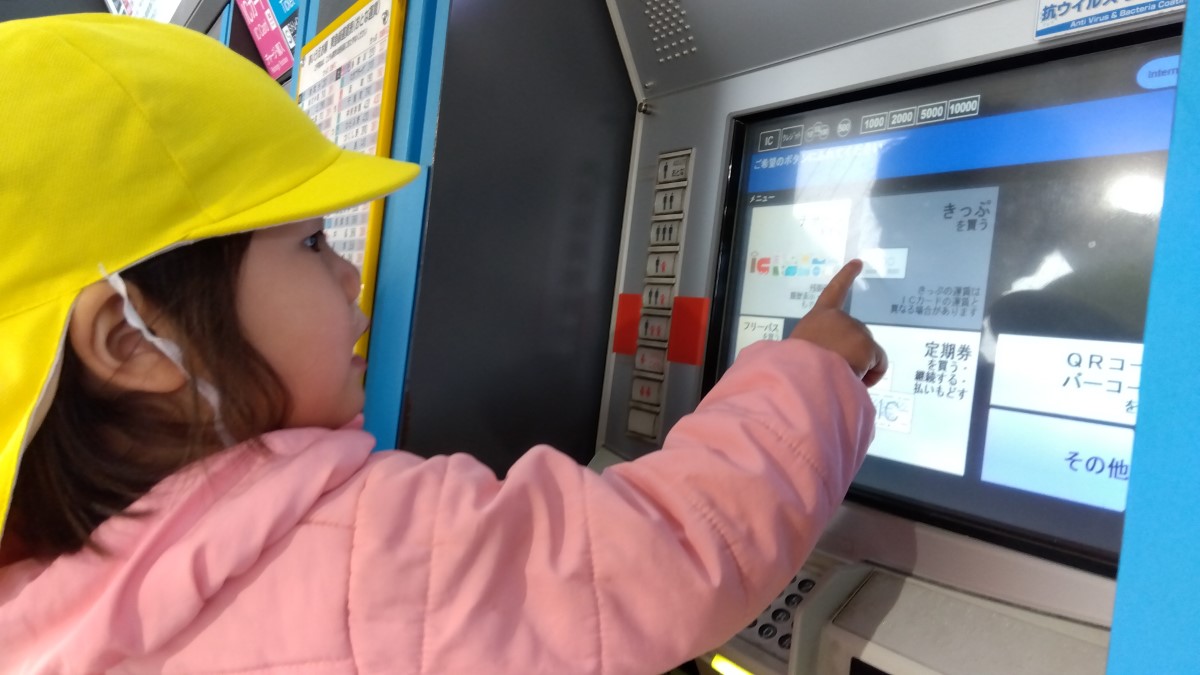 券売機で切符を買う子ども