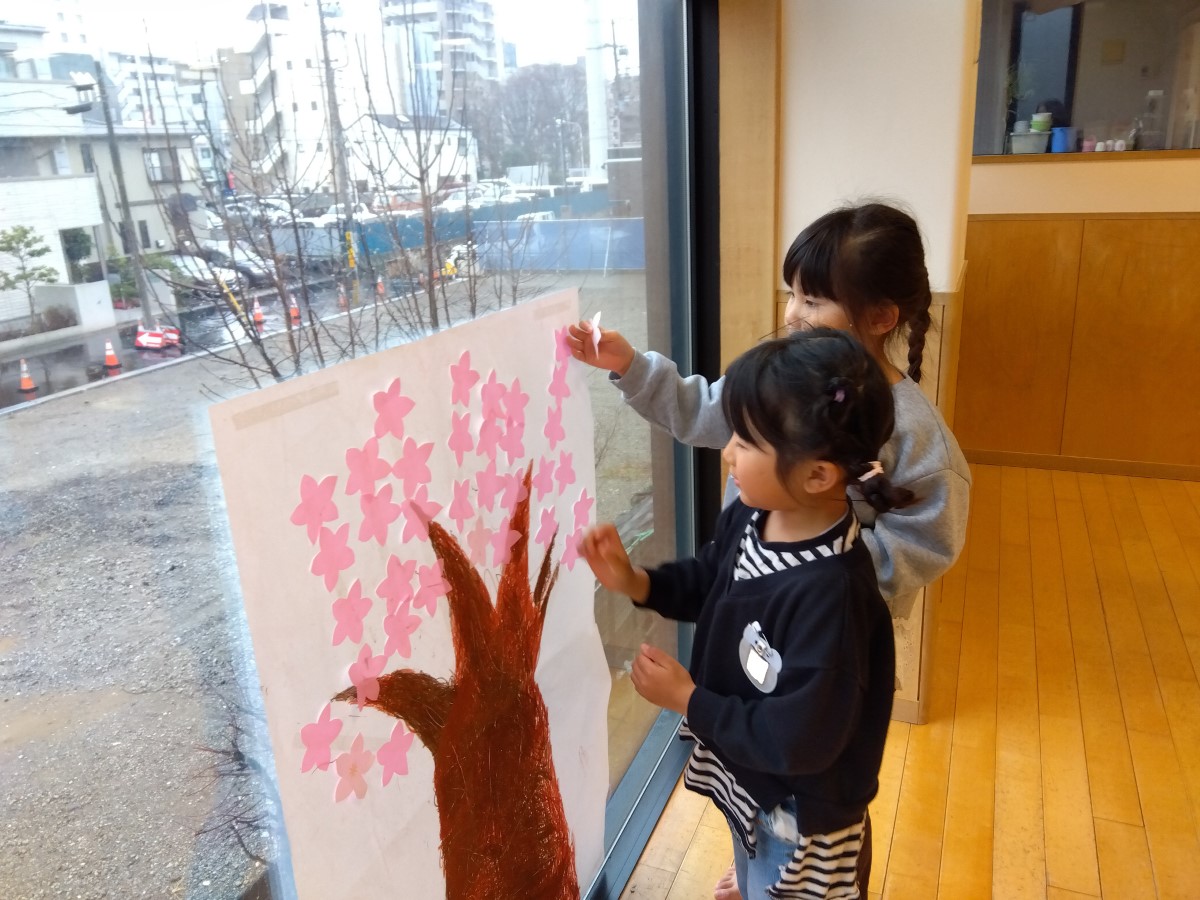 描いた木に花を貼る子どもたち